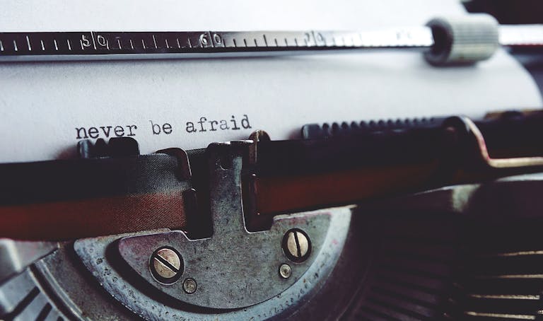 Close-up of a vintage typewriter with the message 'never be afraid' on paper. stop living in fear
